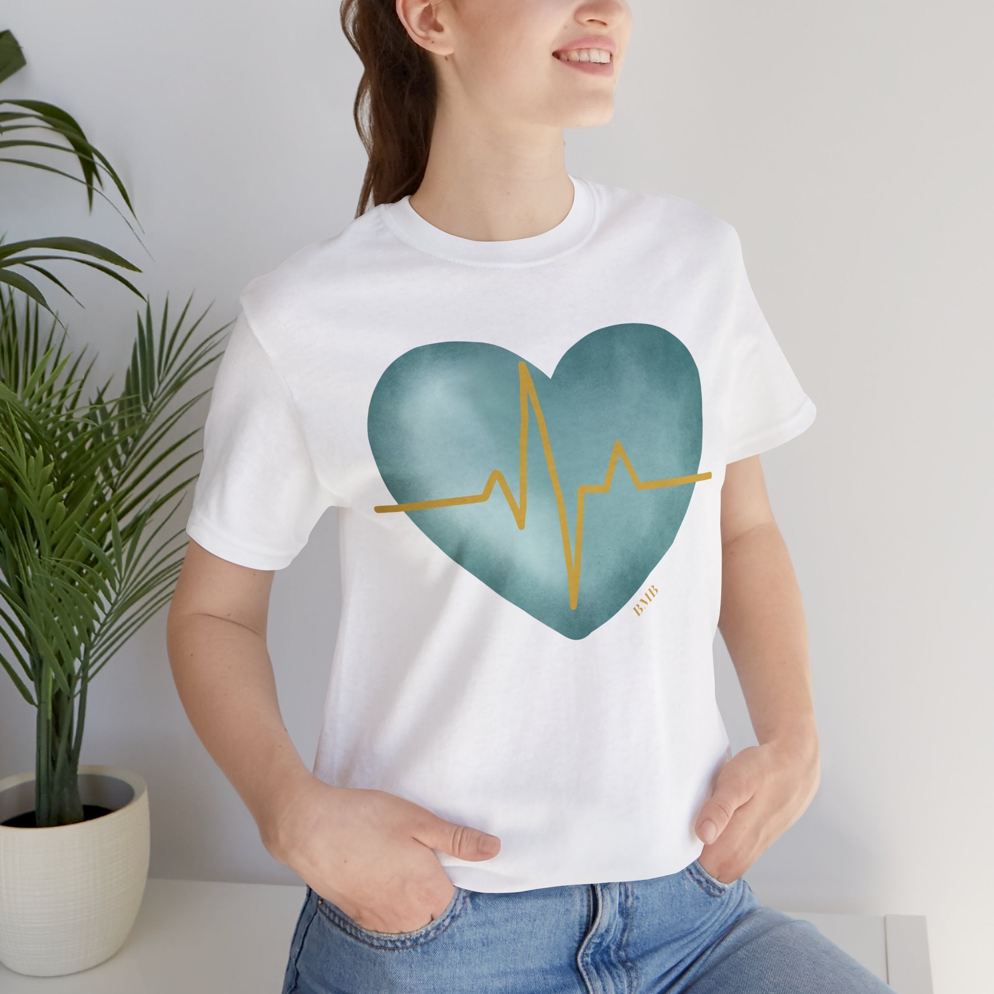 Woman wearing white Heartbeat Heart Tee with teal watercolor heart and gold EKG line — nurse gift shirt
