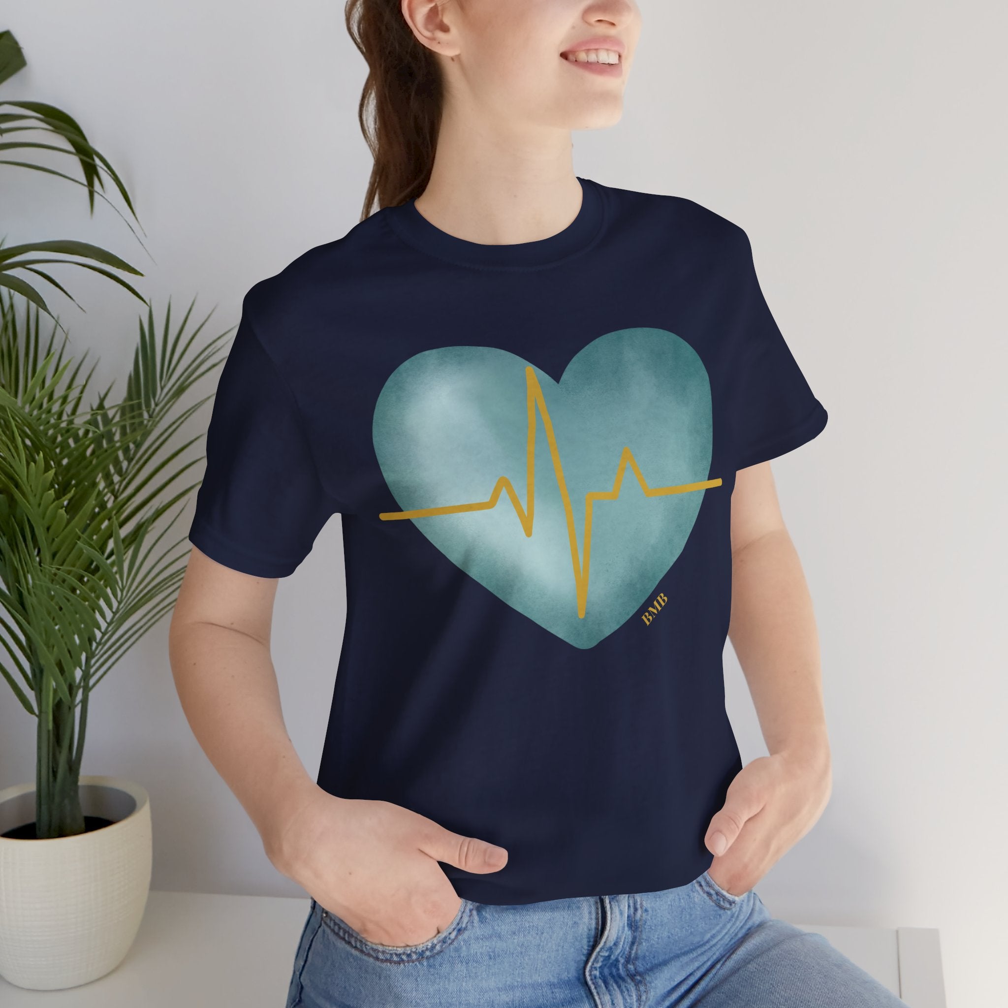 Woman wearing navy Heartbeat Heart Tee with teal watercolor heart and gold EKG line — nurse gift shirt